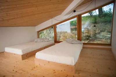 two beds in a room with a large window at Apartment Oton Reya in Dobrovo