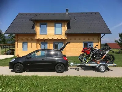a car and a motorcycle parked in front of a house at B&B Woodhouse in Brezje