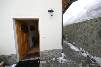 a door to a building with snow on the ground at Apartments Karmen in Rateče