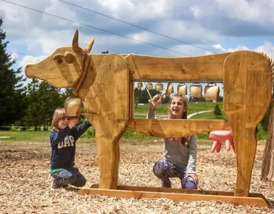 two children playing with a wooden dog on a playground at Rogla - Chalet Mojca Pokrajculja in Zreče