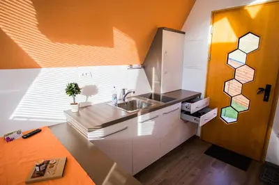 an orange and white kitchen with a sink and a counter at Apartments Beeland Skok in Mozirje