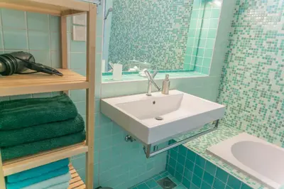 a blue tiled bathroom with a sink and a tub at Tomas's apartment in Ljubljana