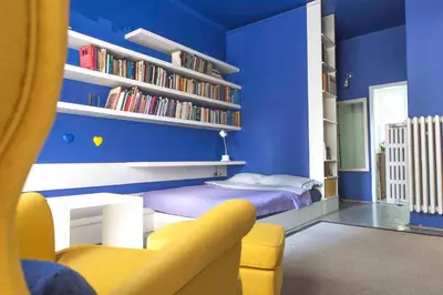 a blue room with a bed and a yellow chair at Taya apartment in Ljubljana