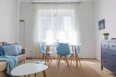a living room with a table and blue chairs at Taya apartment in Ljubljana