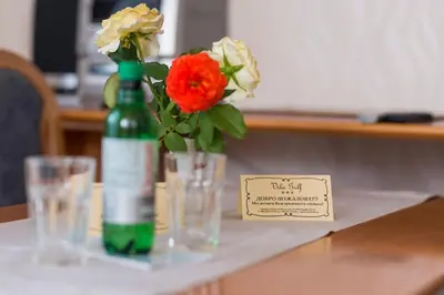 a green bottle with flowers and glasses on a table at Apartment Vila Golf in Rogaška Slatina