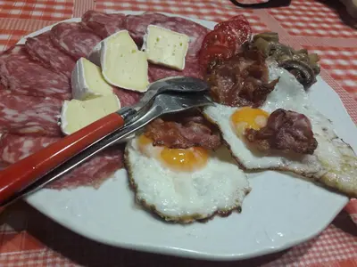 a plate of food with eggs and cheese on a table at Country House Lokev in Lokev