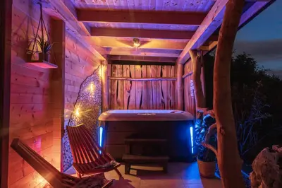 a patio with a hot tub and a hammock at Village Cottage - Koča na vasi in Nazarje