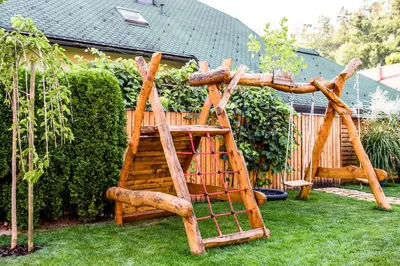 a wooden climbing frame in a garden with a bench at Village Cottage - Koča na vasi in Nazarje