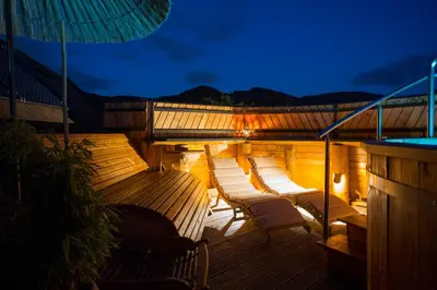 a deck with chairs and an umbrella at night at Village Cottage - Koča na vasi in Nazarje