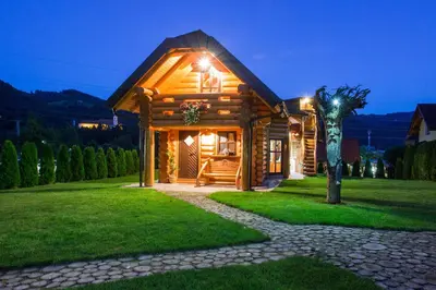 a log cabin with a porch at night at Village Cottage - Koča na vasi in Nazarje