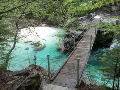 a wooden bridge over a river with blue water at Apartments Wallas in Bovec