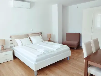 a white bed in a room with a desk and a chair at Apartments Wallas in Bovec