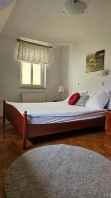 a bedroom with a large bed with white sheets and a window at Guest House Pod Grebenom in Podčetrtek
