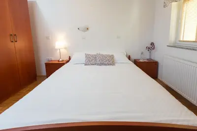 a large white bed in a room with a window at Guest House Pod Grebenom in Podčetrtek