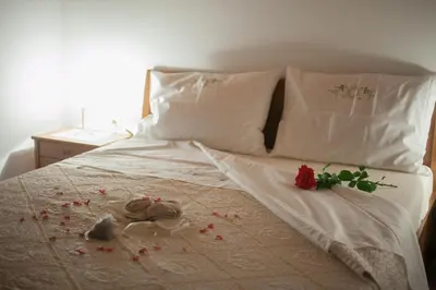 a bed with white sheets and red roses on it at Janezinovi House in Ratečevo Brdo