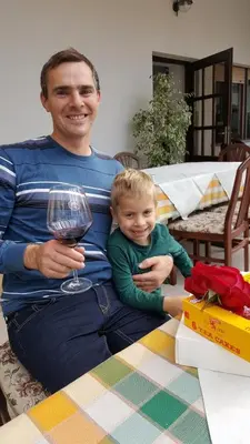 a man holding a child and a glass of wine at Janezinovi House in Ratečevo Brdo