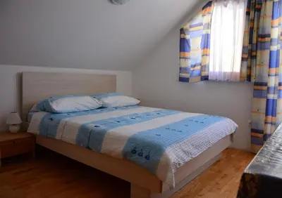 a bedroom with a bed with a blue and white comforter at Apartments Gatej in Cerkno
