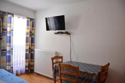 a room with a table and a tv on the wall at Apartments Gatej in Cerkno