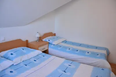 two beds in a bedroom with blue and white sheets at Apartments Gatej in Cerkno