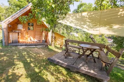 a picnic table and chairs in front of a cabin at Glamping Organic Farm Slibar in Tržič