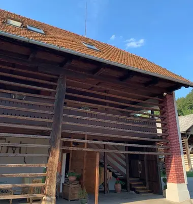 a large wooden building with a red roof at Martinova izba - Rooms & Apartments in Laško