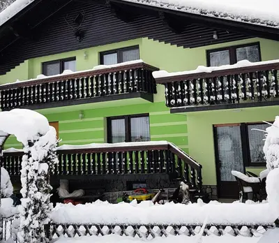 a green house with snow on the outside of it at Zeleni apartma Zreče in Zreče