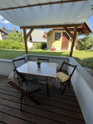 a table and two chairs on a deck with a roof at Apartma Slivnik in Spodnje Gorje
