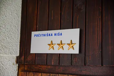 a sign on a wooden door with three gold stars at Holiday Home Vila Kopriva in Gozd Martuljek