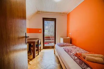 a bedroom with orange walls and a bed and a desk at Holiday Home Vila Kopriva in Gozd Martuljek