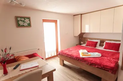 a bedroom with a bed with a red bedspread and a table at EkoTurizem Viženčar in Cerklje na Gorenjskem