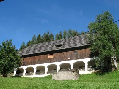 a large wooden barn with arches in a field at Tourist farm Gradišnik in Solčava