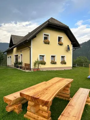 a wooden picnic table in front of a house at Tourist farm Gradišnik in Solčava