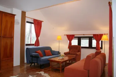 a living room with red curtains and a couch and chairs at Apartments Lovšin in Mozirje