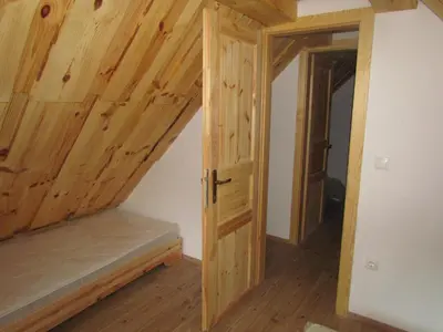 an attic room with wooden walls and a door at Fikfak cottage in Bled