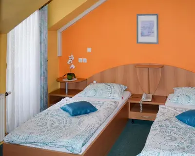 two beds in a room with an orange wall at Penzion Gostilna Keber in Domžale