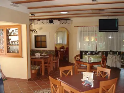 a restaurant with tables and chairs and a flat screen tv at Penzion Gostilna Keber in Domžale