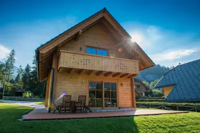 a log cabin with a deck and chairs in a yard at Brunarica Murka in Bohinj