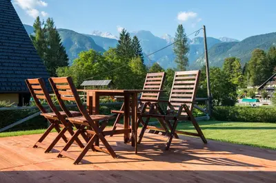 three chairs and a wooden table with a view of mountains at Brunarica Murka in Bohinj