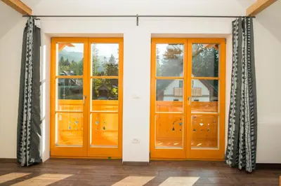 two wooden doors with curtains in a room at Brunarica Murka in Bohinj