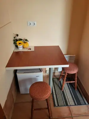 a kitchen with a wooden table and two stools at Apartma na Starem Placu in Idrija