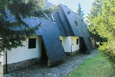 a house with a blue roof with a stone walkway at Apartments Rogla in Zreče