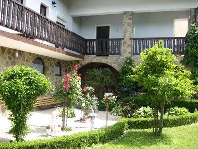 a garden in front of a building with trees and flowers at Hiša Koražija in Rogaška Slatina