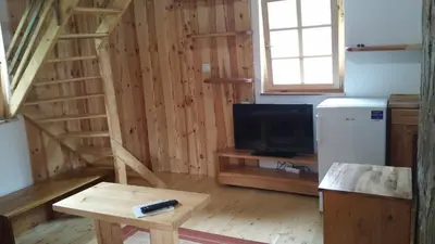 a living room with a tv and a table and a refrigerator at Tourist farm Samec in Sele