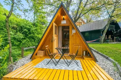 a house with a triangular roof on a wooden deck at Resort pod orehi - Bled - Apartma & Glamping & Savna in Bled