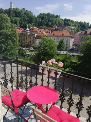 a pink table and chairs on a balcony with a city at Codelli Deluxe Fresco City Centre APP With Balcony in Ljubljana
