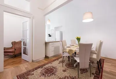 a dining room with a table and chairs and a kitchen at Codelli Deluxe Fresco City Centre APP With Balcony in Ljubljana