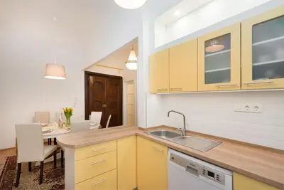 a kitchen with yellow cabinets and a dining room at Codelli Deluxe Fresco City Centre APP With Balcony in Ljubljana