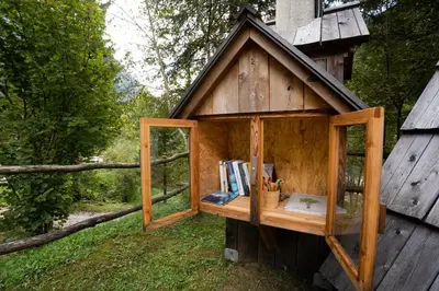 a small wooden building with a window and books at Camp Korita in Soča
