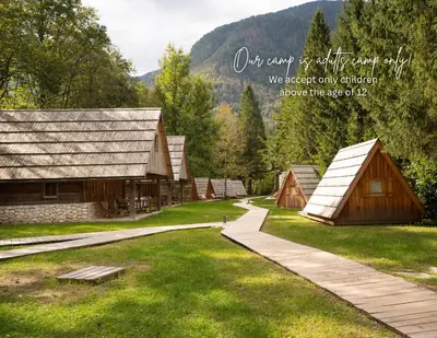 a group of small wooden buildings in a field at Camp Korita in Soča