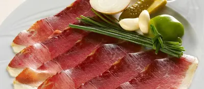 a piece of meat on a white plate with vegetables at Tourist Farm Ferencovi in Cankova